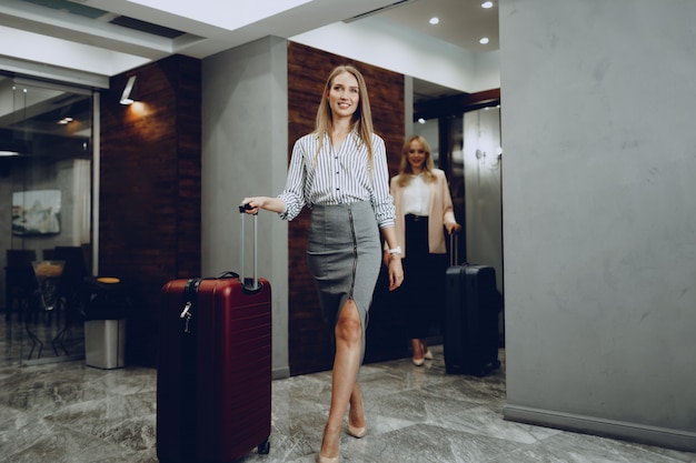 Dos mujeres jóvenes en ropa formal entrando en el vestíbulo del hotel