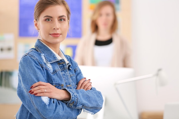 Dos mujeres jóvenes sentadas cerca del escritorio con un plan de instrumentos y una computadora portátil