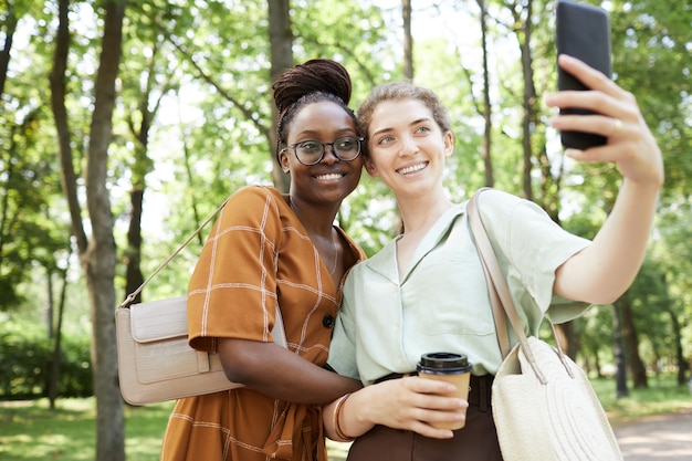 Dos mujeres jóvenes sonrientes tomando Selfie en el parque