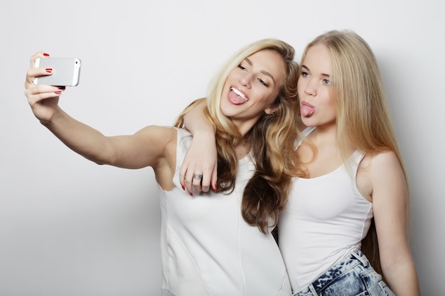 Dos mujeres jóvenes tomando selfie con teléfono móvil