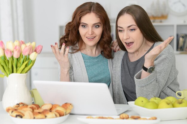 dos, mujeres jóvenes, usar la computadora portátil, y, bebida, té