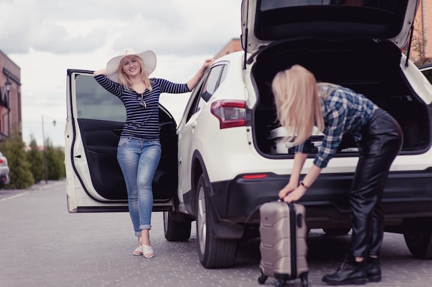 Dos mujeres jóvenes van a viajar en auto