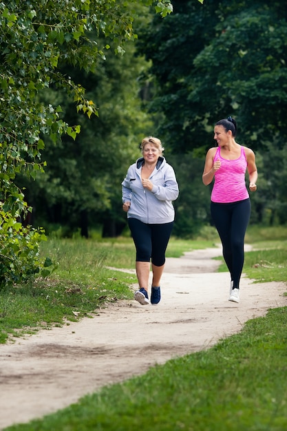 Dos mujeres jóvenes y viejas practican deportes y corren en el parque