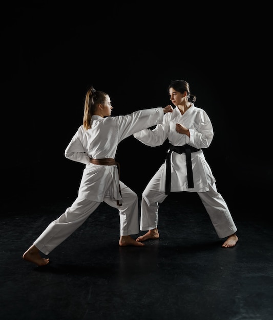 Dos mujeres karatekas en kimono blanco, huelga en acción. Luchadores de karate en entrenamiento, artes marciales, competencia de lucha de mujeres