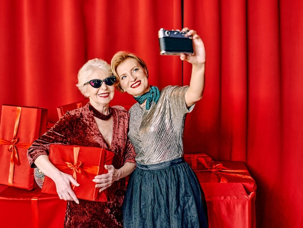 Dos mujeres mayores en la fiesta haciendo selfie sosteniendo una cámara de cine. Fiesta, celebración, tecnología.