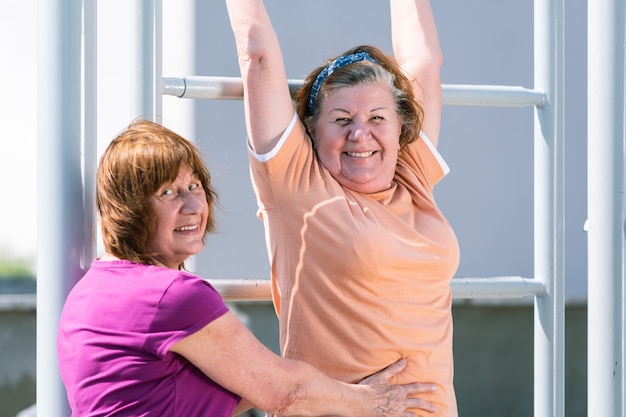 Dos mujeres mayores practicando fitness en el campo de deportes exterior