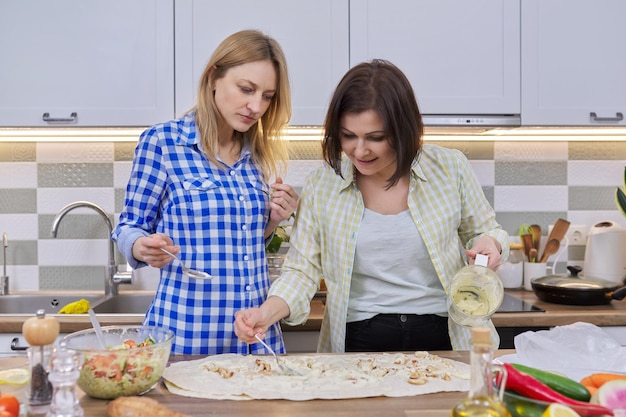 Dos mujeres de mediana edad cocinando juntas en casa en la cocina