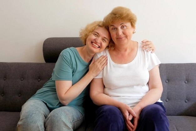 Dos mujeres de mediana edad sentadas en el sofá y sonriendo en la sala de estar en el interior