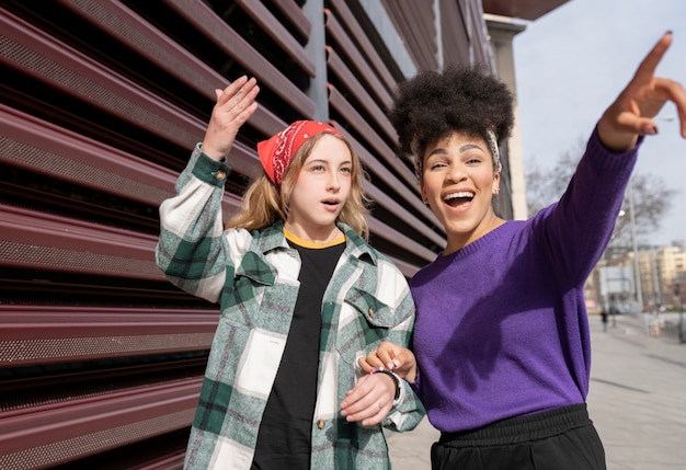 Dos mujeres multirraciales alrededor de la ciudad apuntando a algo