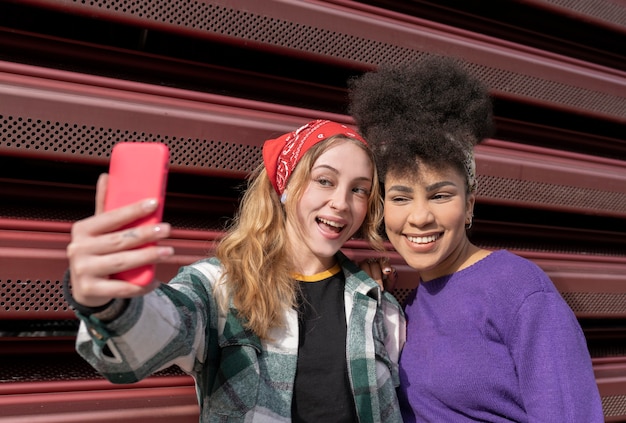 Foto dos mujeres multirraciales tomando selfie en la calle