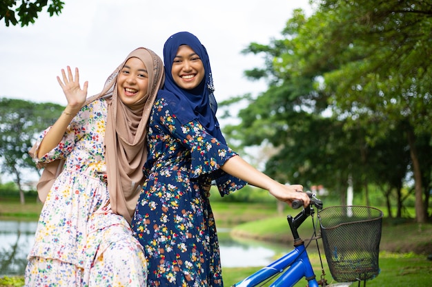 Dos mujeres musulmanas andan en bicicleta para viajar en el jardín.