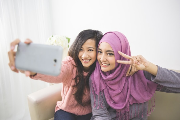 Dos mujeres musulmanas jóvenes felices toman autorretrato