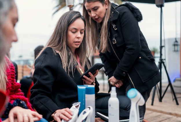 Dos mujeres de negocios interactuando entre sí mirando un teléfono celular al aire libre
