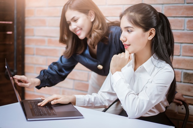 Dos mujeres de negocios jóvenes son información analítica en la pantalla del portátil, reunión de negocios