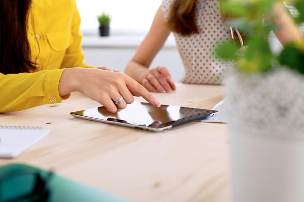 Dos mujeres de negocios o amigos están hablando y usando una tableta.