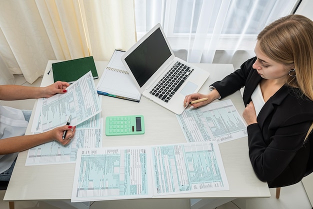 Dos mujeres de negocios que llenan el formulario de impuestos en la contabilidad del trabajo en equipo de la oficina
