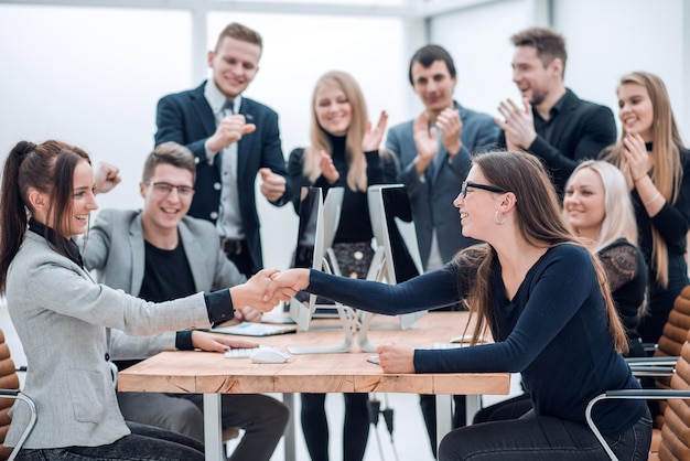 Dos mujeres de negocios sonrientes dándose la mano