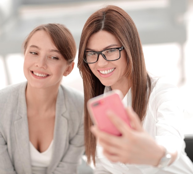 Dos mujeres de negocios tomando selfies en la oficina