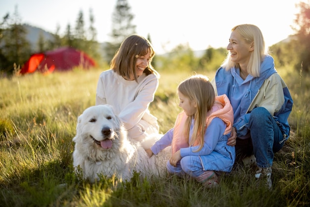 Dos mujeres con niña y perro en la naturaleza.