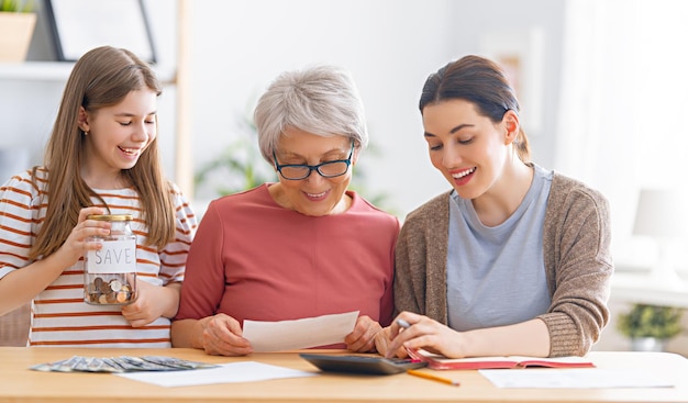 Dos mujeres y un niño sentados en el escritorio con un recibo en papel, calculan los gastos y administran el presupuesto familiar.