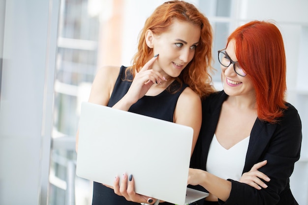 Dos mujeres pelirrojas trabajan juntas en la oficina moderna