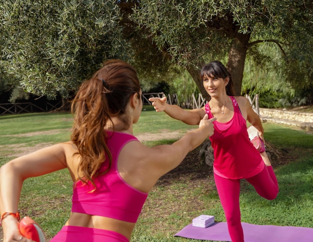 Dos mujeres practicando pilates en el parque en un día soleado de verano