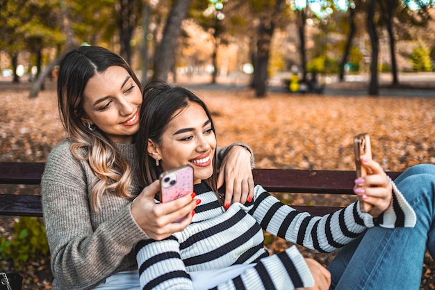 Dos mujeres sentadas en un banco mirando un teléfono celular