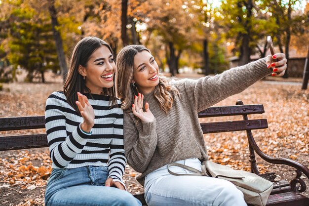 Dos mujeres sentadas en un banco tomando una selfie