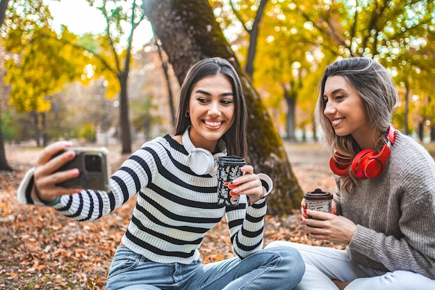 Dos mujeres sentadas en el parque una sosteniendo una taza de café