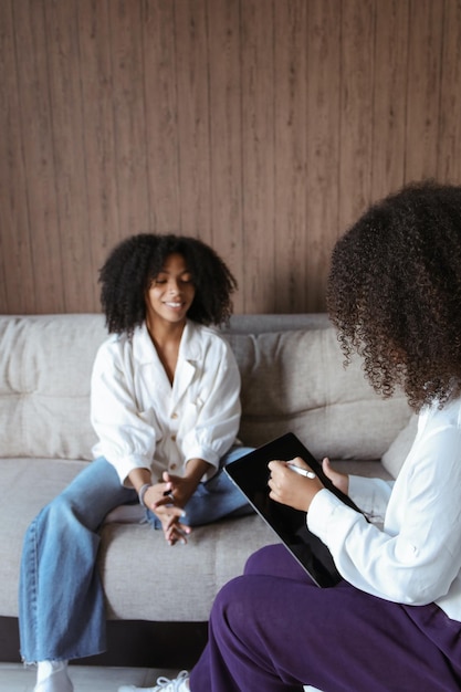 Dos mujeres sentadas en un sofá, una de ellas usa jeans y la otra sostiene una tableta.