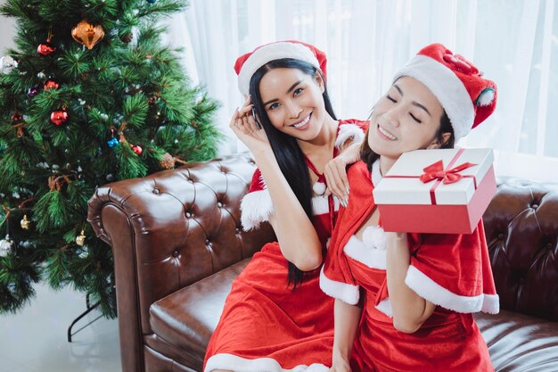 Dos mujeres sexy de Santa sosteniendo cajas de regalo con sonrisa feliz juntos en casa en el festival de Navidad.