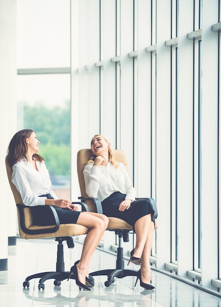 Las dos mujeres en las sillas hablan en el pasillo de la oficina.