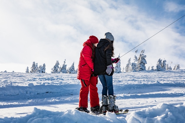 Dos mujeres snowboarder y esquiador tirando hacia arriba por la colina en el espacio de copia del yugo
