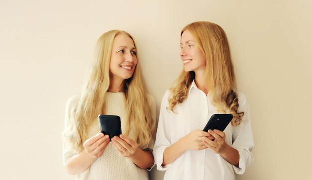 Foto dos mujeres con teléfono móvil mirándose una a la otra madre de mediana edad y hija adulta juntos
