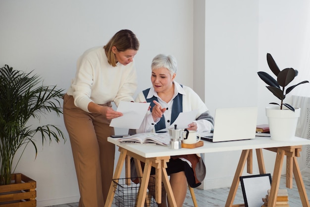 Dos mujeres trabajando juntas en el lugar de trabajo con escritorio y computadora portátil