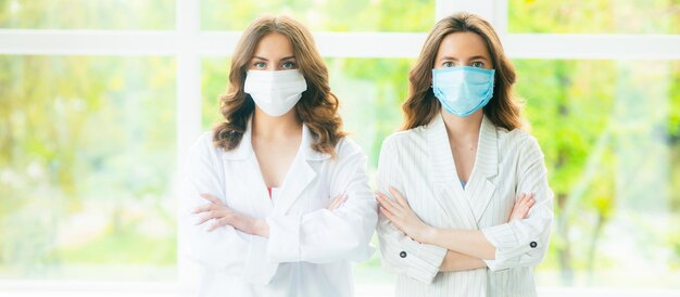 Dos mujeres con trajes médicos protectores y mascarillas