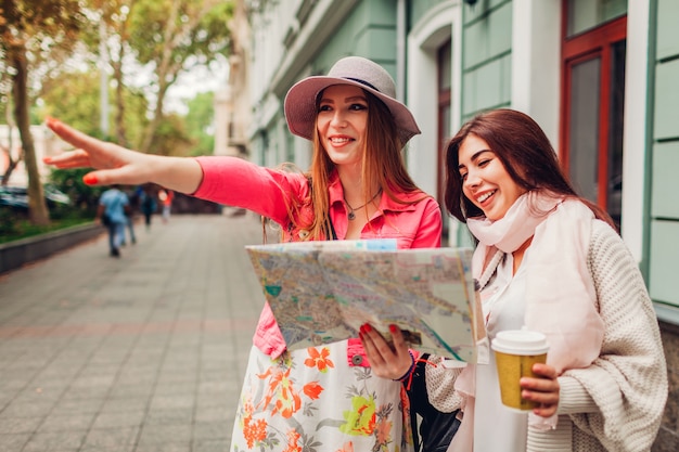 Dos mujeres turistas buscando el camino correcto en Odessa. Amigos felices viajeros que muestran dirección