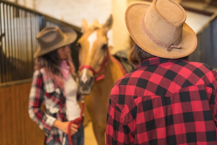 Foto dos mujeres vaqueras acariciando un caballo, con trajes de américa del sur, el estilo de vida de dos mujeres que trabajan en un establo
