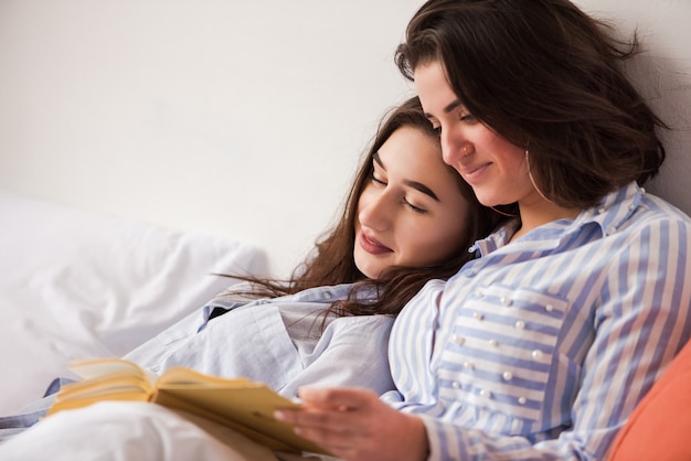 Dos mujeres yacían en la cama con libro de papel