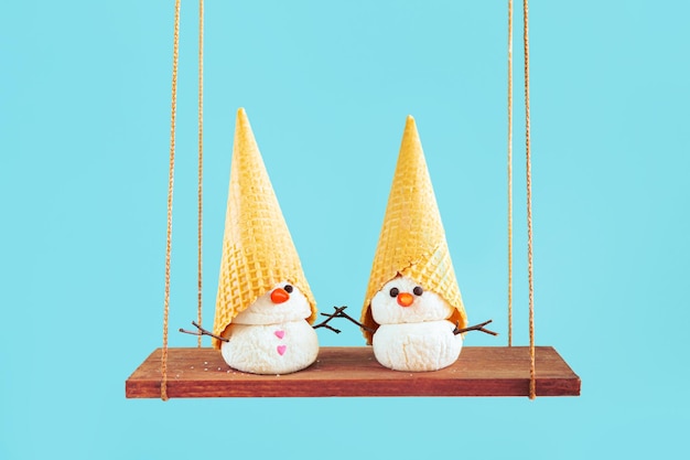 Dos muñecos de nieve de helado se columpian en un columpio