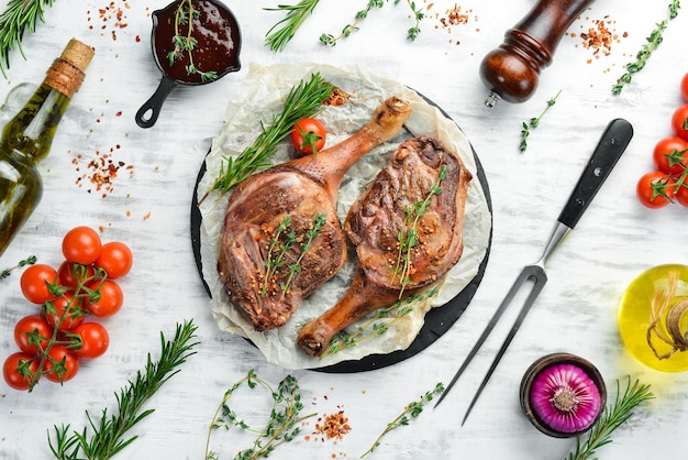 Dos muslos de pato al horno con especias y verduras sobre un fondo de madera blanca Vista plana Vista superior