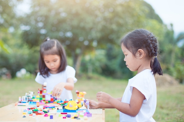 Dos niña asiática linda del niño jugando con coloridos bloques juntos.