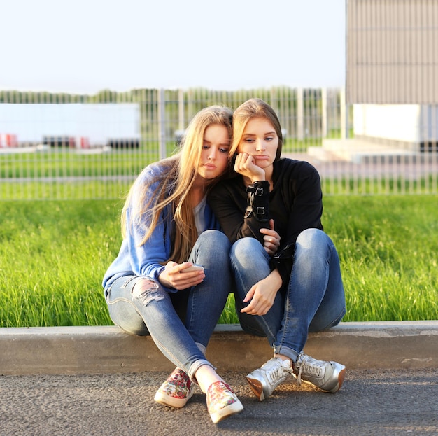 dos, niñas adolescentes, sentado, juntos, aire libre