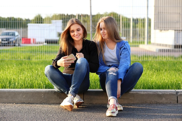 dos, niñas adolescentes, utilizar, teléfono inteligente, tomar, un, selfie, sentado, juntos