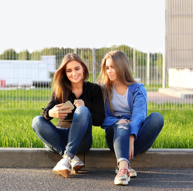 dos, niñas adolescentes, utilizar, teléfono inteligente, tomar, un, selfie, sentado, juntos