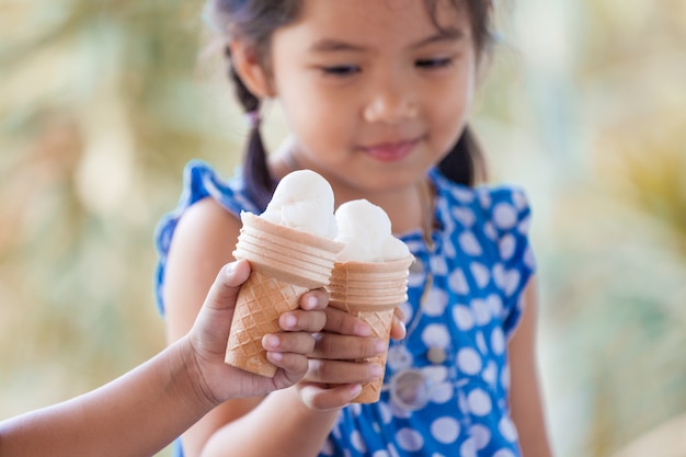 Dos niñas asiáticas que sostienen el cono de galleta de fusión del helado junto en tono del color del vintage
