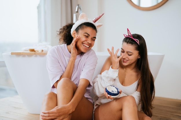 Dos niñas en el baño jugando con crema para la cara