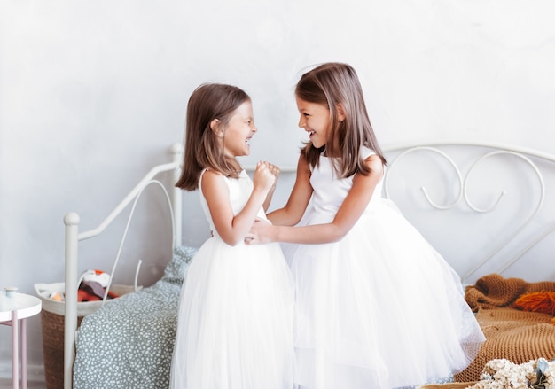 Dos niñas bonitas se divierten en una habitación luminosa. Los niños encantadores divertidos se divierten