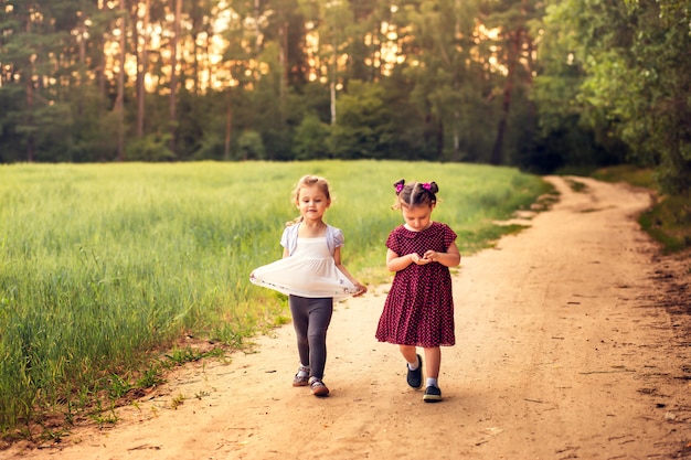 Dos niñas caminan por un sendero del bosque en verano