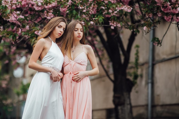 Dos niñas cerca de un árbol en flor. Por ejemplo, un retrato de una joven y bella dama de moda.